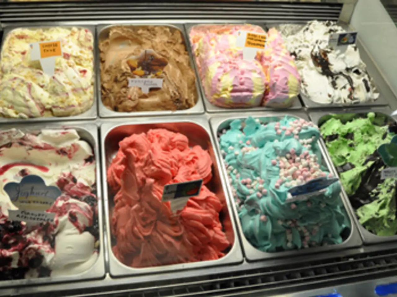 In this image there are different flavors of ice creams in the trays and a name board to each ice...