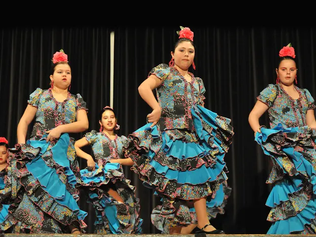 This picture shows few women dancing on the dais and we see black color cloth on the back. All the...