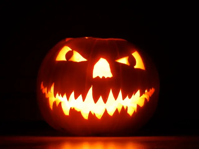 In the foreground of this image, there is a carved pumpkin on the floor and the dark background.