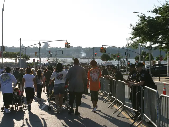Here we can see few persons are walking on the road and among them few are pushing strollers. In...
